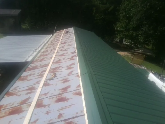Old rusted panels beside newly installed green metal roofing — Wind Damage Roof Repair by Roofing Brothers in Copper Hill