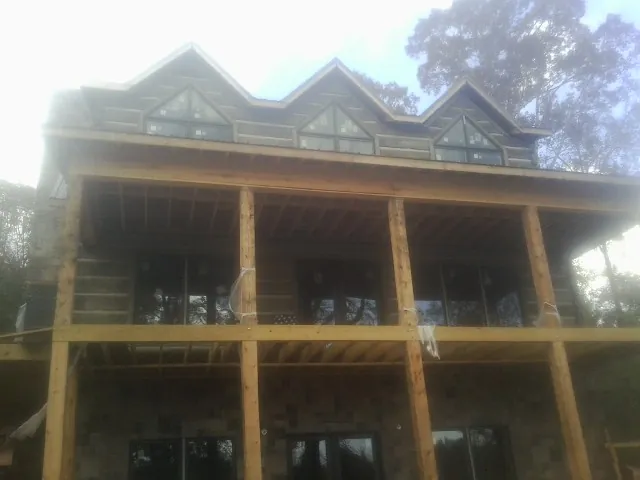 Dormers and porch framing on a large log home under construction — Roof Coating work by our crew in Copper Hill