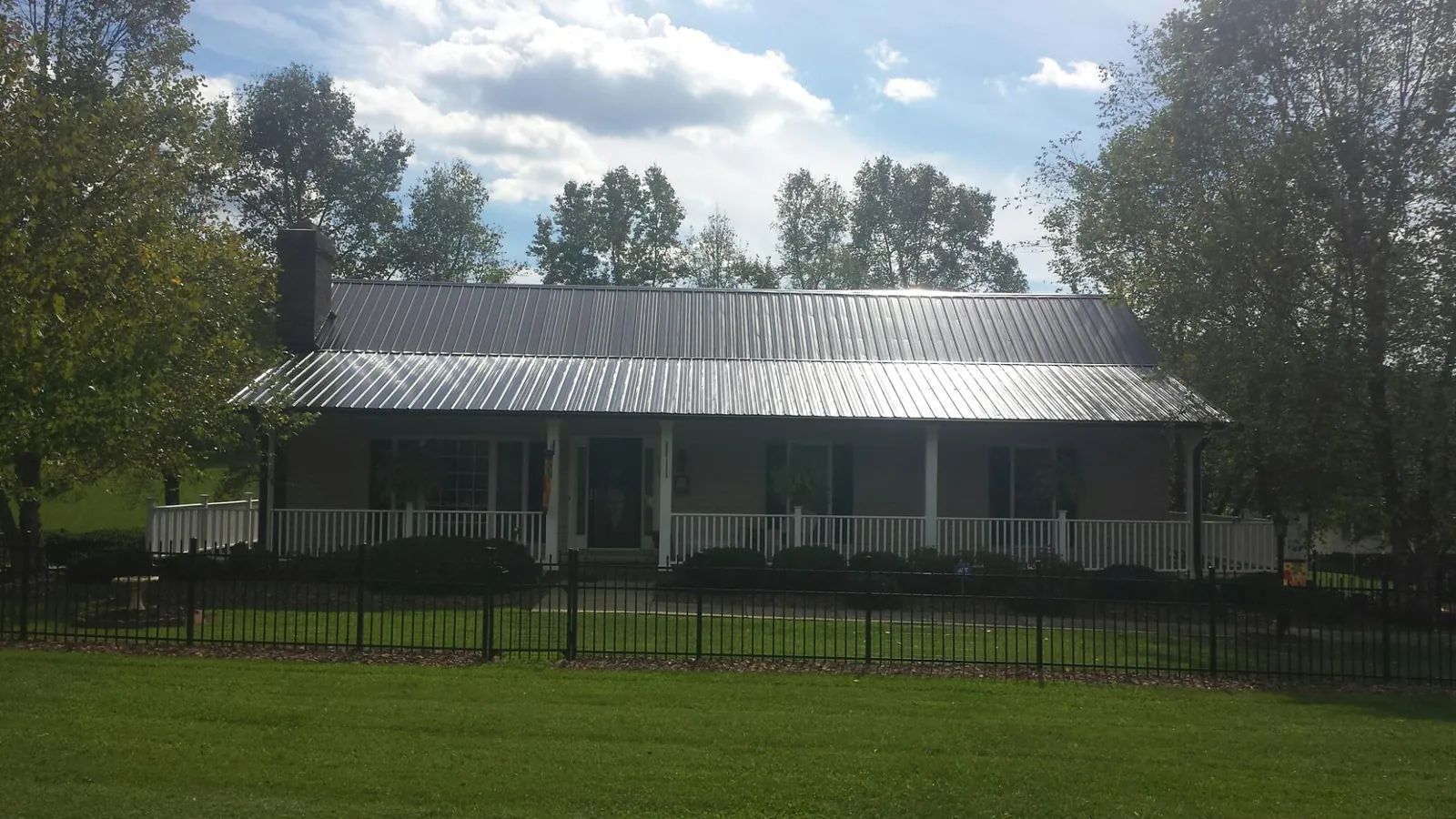 Gray metal roof on a brick ranch with a full width front porch — Gutter Guard Installation work by our crew in Copper Hill