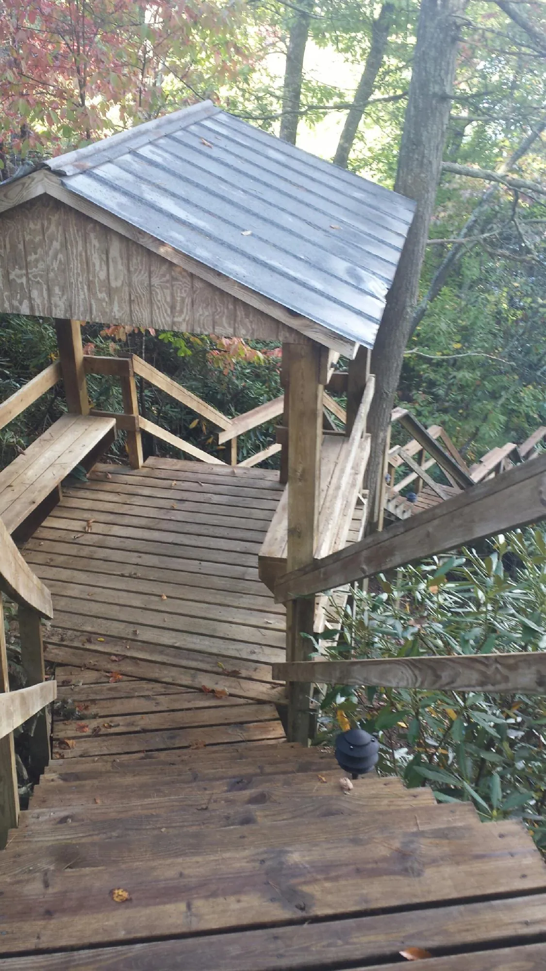 Metal roofed shelter over wooden steps on a wooded walkway — Skylight Repair & Installation work by our crew in Copper Hill