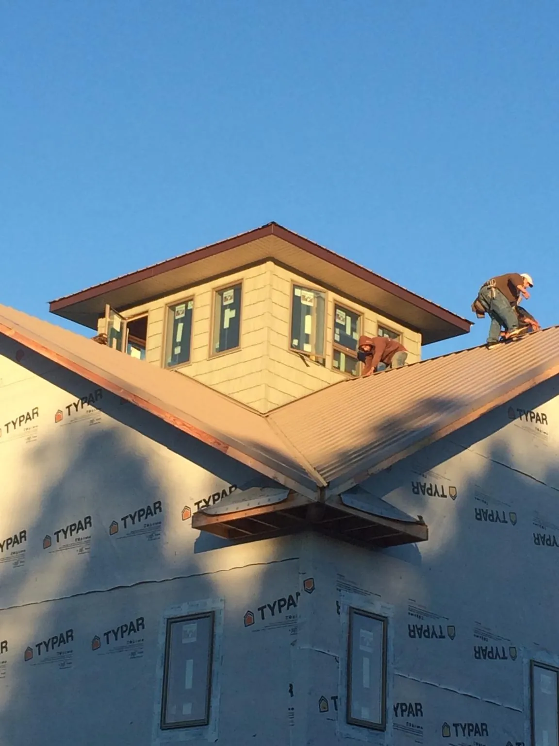 Roofers working around a rooftop cupola on a new metal roof at sunset — Roof Waterproofing in Copper Hill by Roofing Brothers